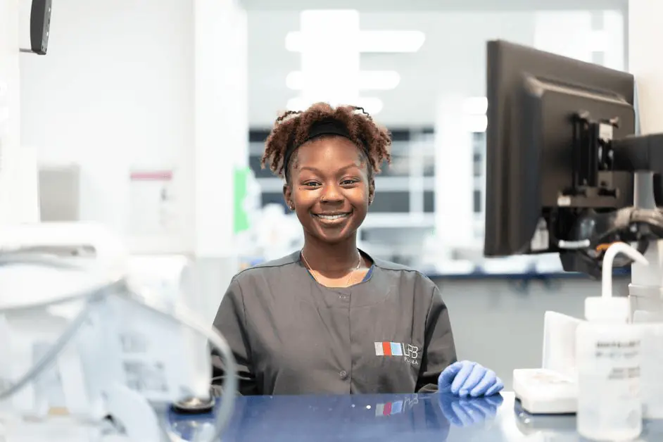 An LFB employee, standing behind a counter, is smiling and ready to screen potential donors
